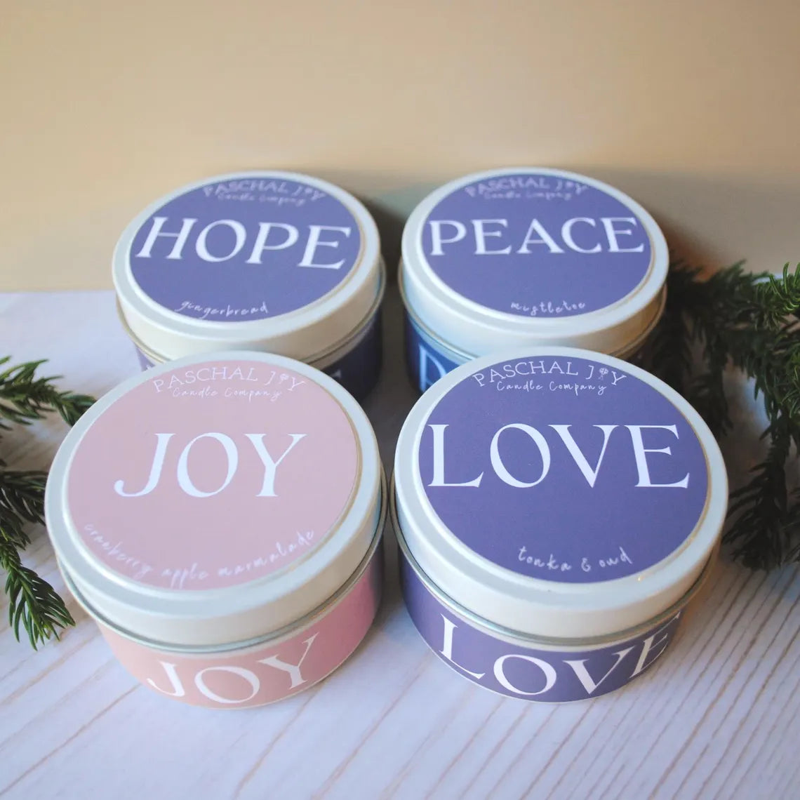 Four candles in tins with 'Hope', 'Peace', 'Joy', and 'Love' text on lids.