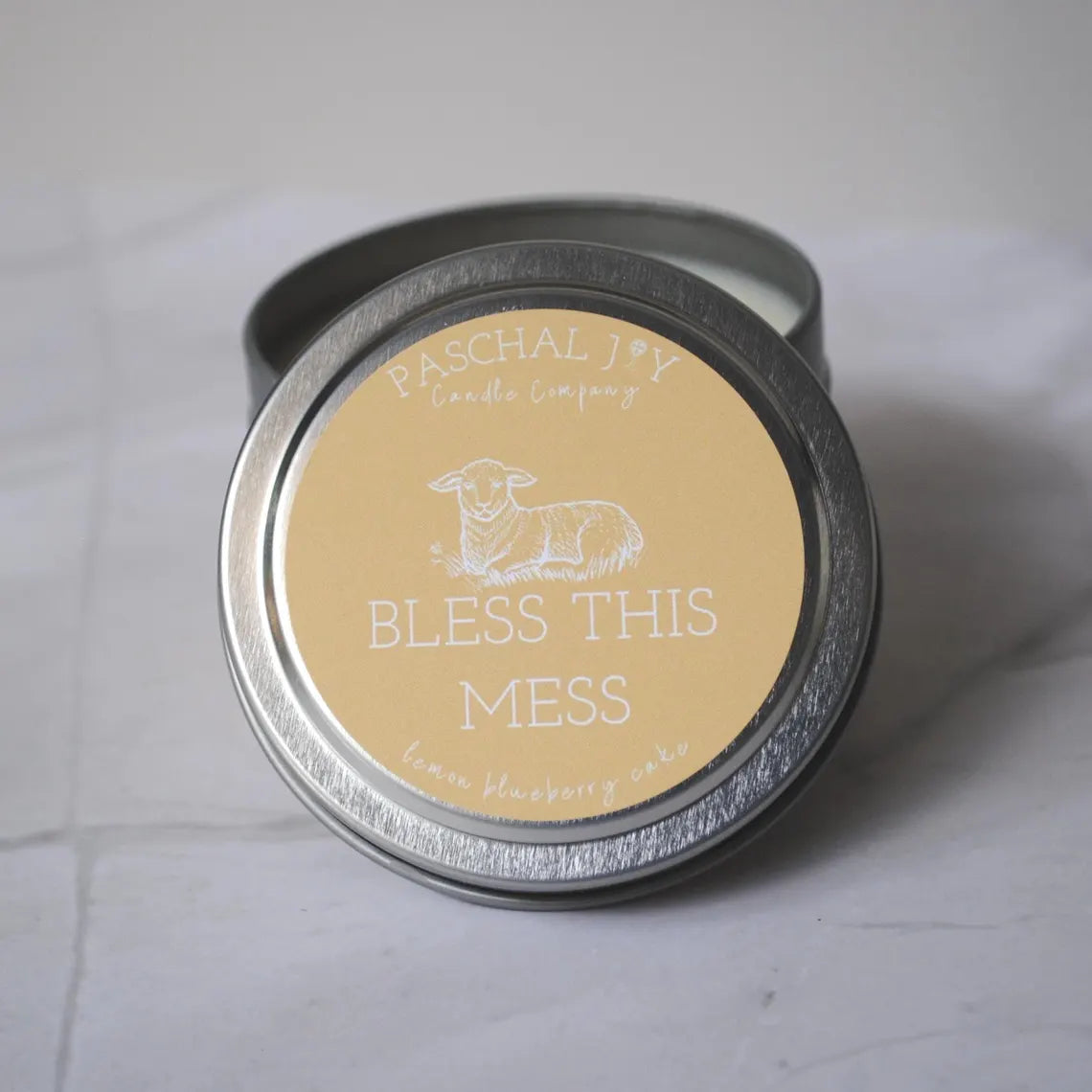 Front lid view of BLESS THIS MESS candle tin on grey background