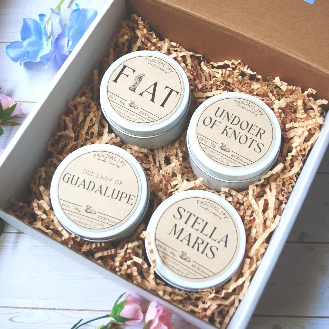 Fiat, Guadalupe, Stella Maris, and Undoer of Knots candle tins in a gift box with flowers