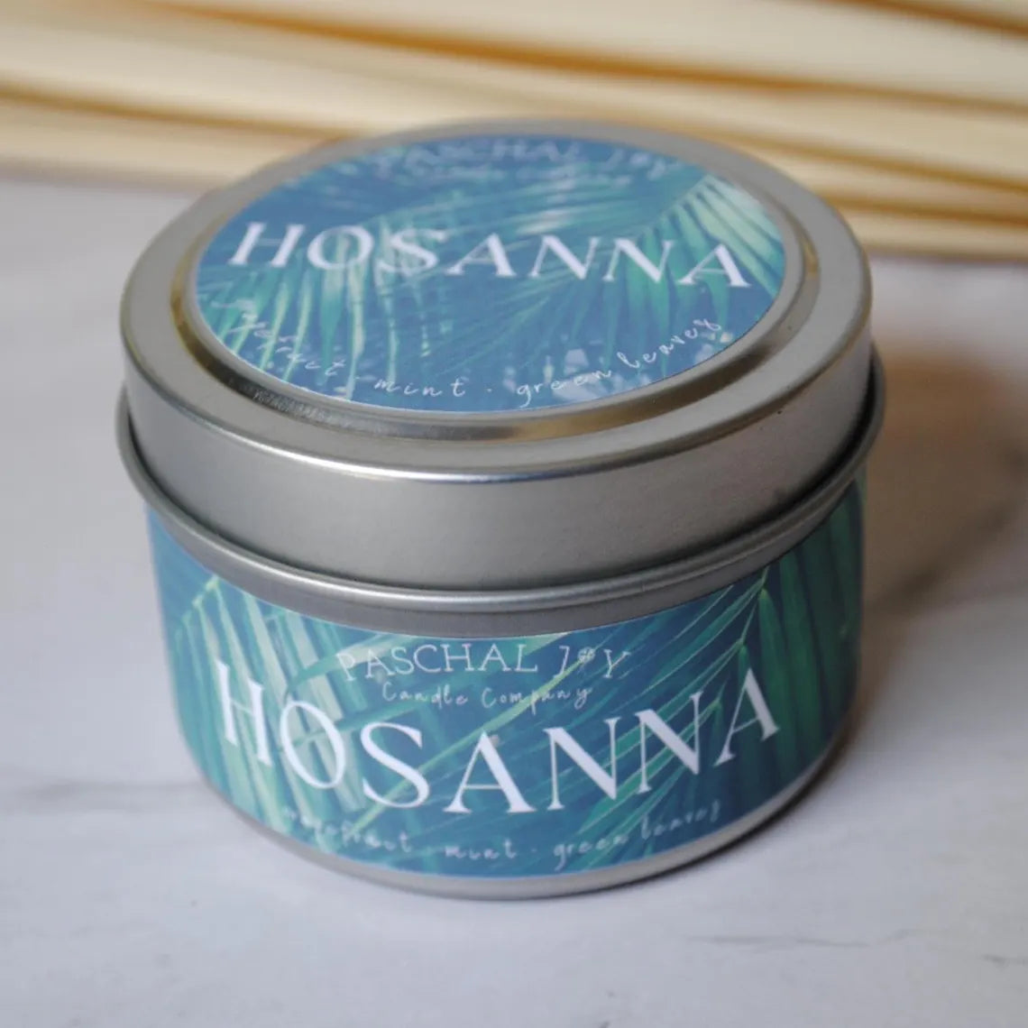 Hosanna Candle Tin with palm leaves in background