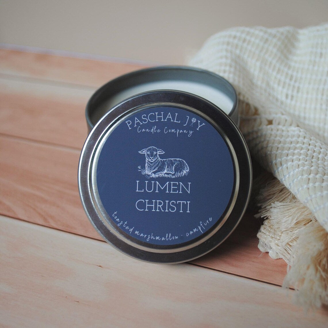 Candle tin with 'Paschal Joy Candle Company' label on a wooden surface