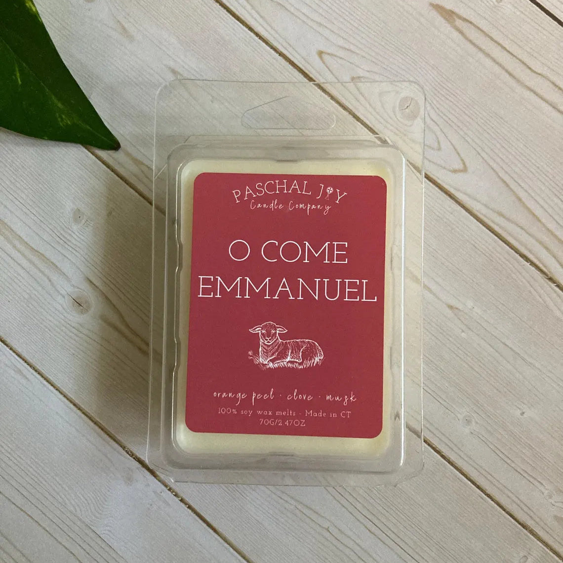 Wax melt in a clear container with a red label on a wooden surface