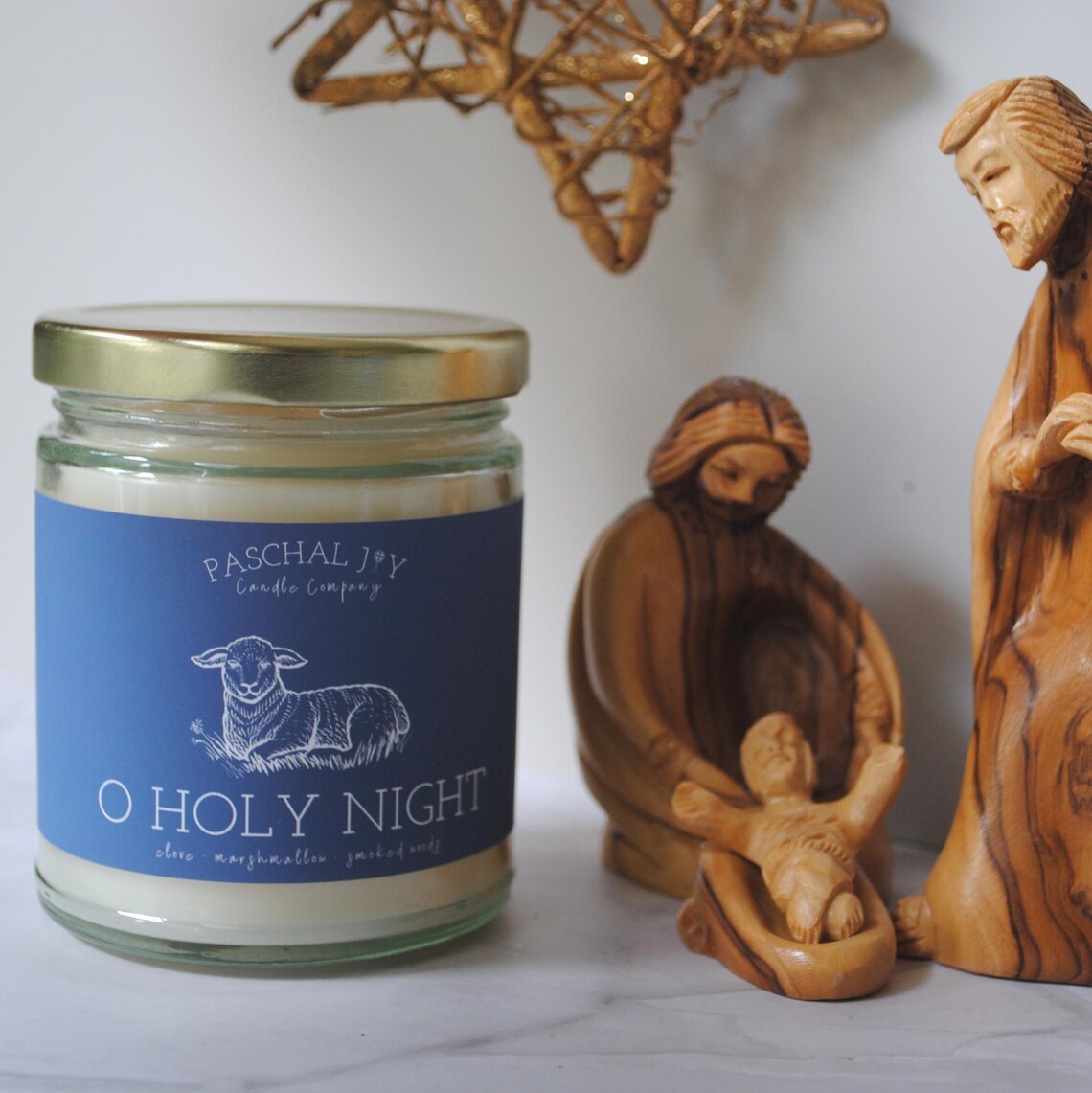 Candle jar labeled 'O Holy Night' with nativity scene figurines on a white surface.