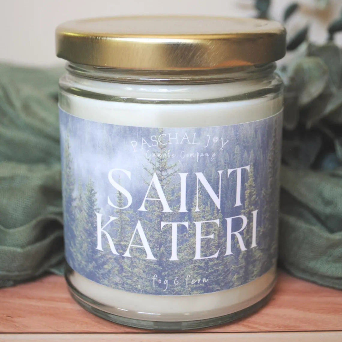 Saint Kateri candle on wood background with green cloth and leaves