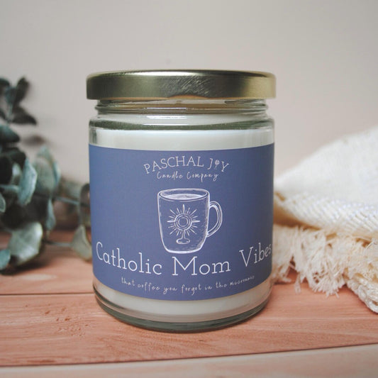 Candle jar with 'Catholic Mom Vibes' label on a wooden surface