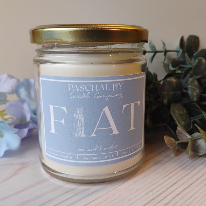 Candle with FIAT label, flowers and greenery in background
