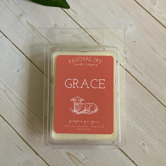 Wax melt in a clear packaging with 'Pascchal Joy Candle Company' label on a wooden surface