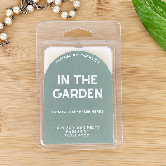 Light green wax melt container IN THE GARDEN, TOMATO LEAF AND FRESH HERBS. Pearl rosary in background