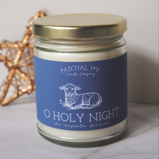 Candle jar with blue label featuring a sheep and text, on a light background