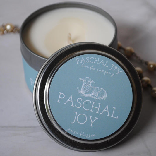 Candle in a tin with 'Paschal Joy' label on a light background