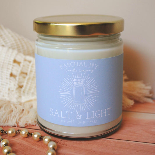 Candle jar labeled 'Salt & Light' with a gold lid on a wooden surface.