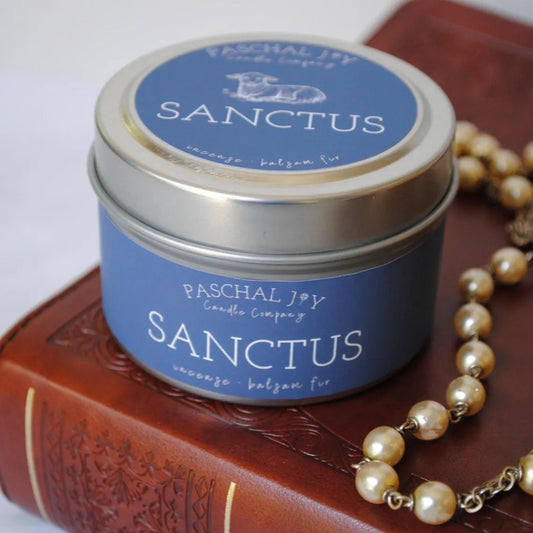 Sanctus candle tin on top of bible with a rosary