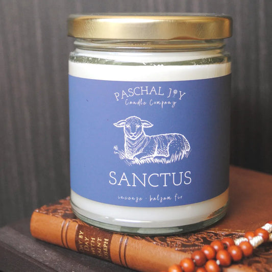Sanctus Midnight Mass Incense Candle on top of saints book with a wooden rosary