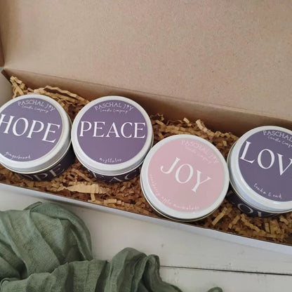 Four small advent candles in a box with 'Hope', 'Peace', 'Joy', and 'Love' text on lids.