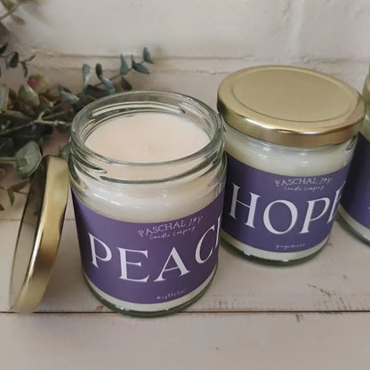 Two candles in jars with purple labels on a wooden surface.